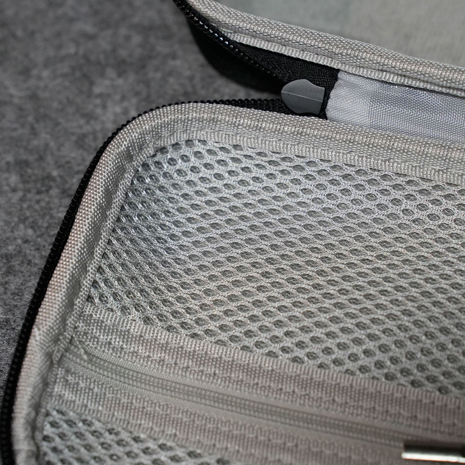 Close-up of a MonsGeek Keyboard Carrying Case with a zipper on a textured surface