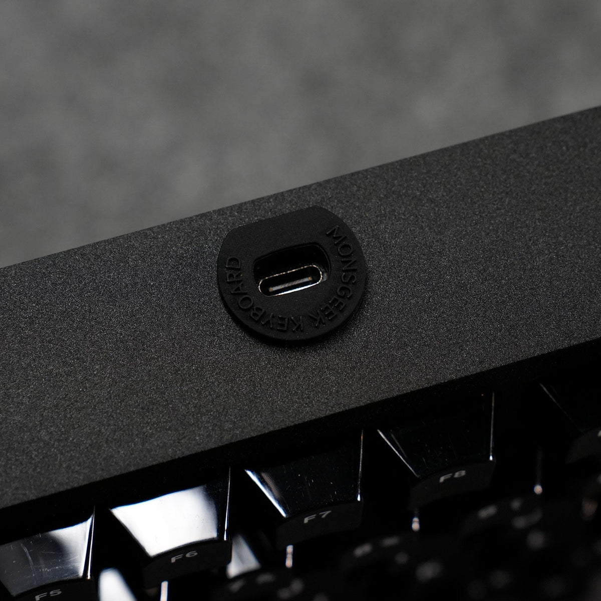 Close-up of a USB port on a black MonsGeek M1 V5 HE Magnetic Keyboard with a blurred background